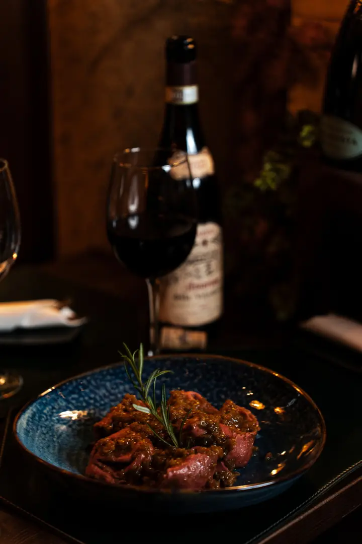 Piatto della tradizione veronese con rosmarino e una bottiglia di Amarone – Punto Rosa Verona